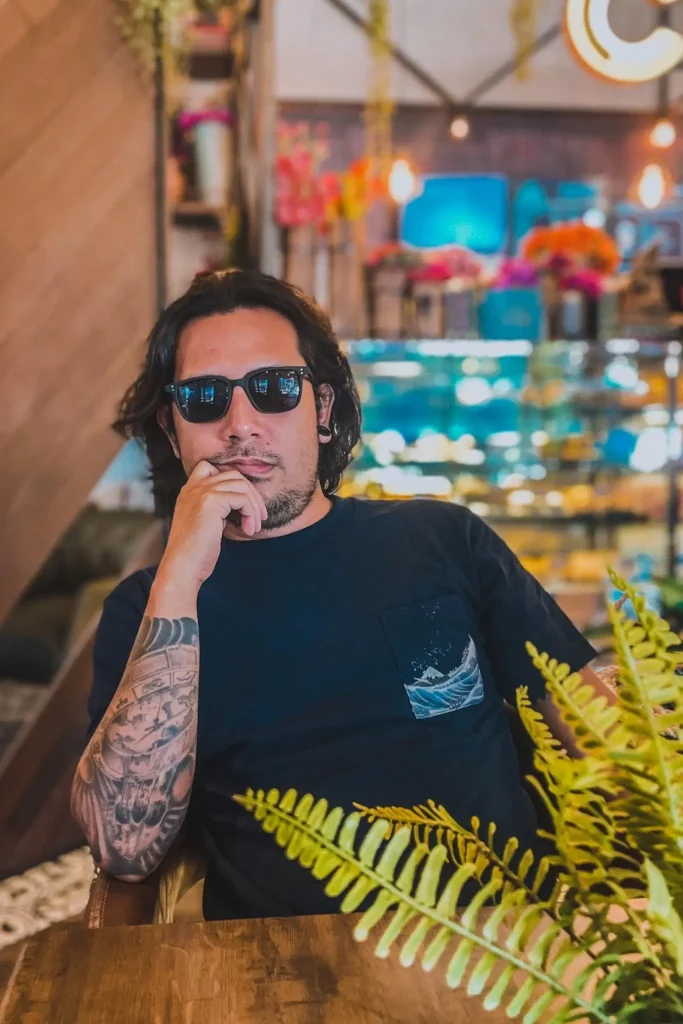 Noel Miranda, founder and WordPress developer at NM WebWorks, seated in a café wearing sunglasses