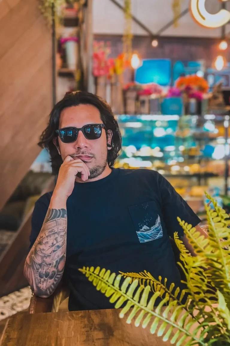 Noel Miranda, founder and WordPress developer at NM WebWorks, seated in a café wearing sunglasses